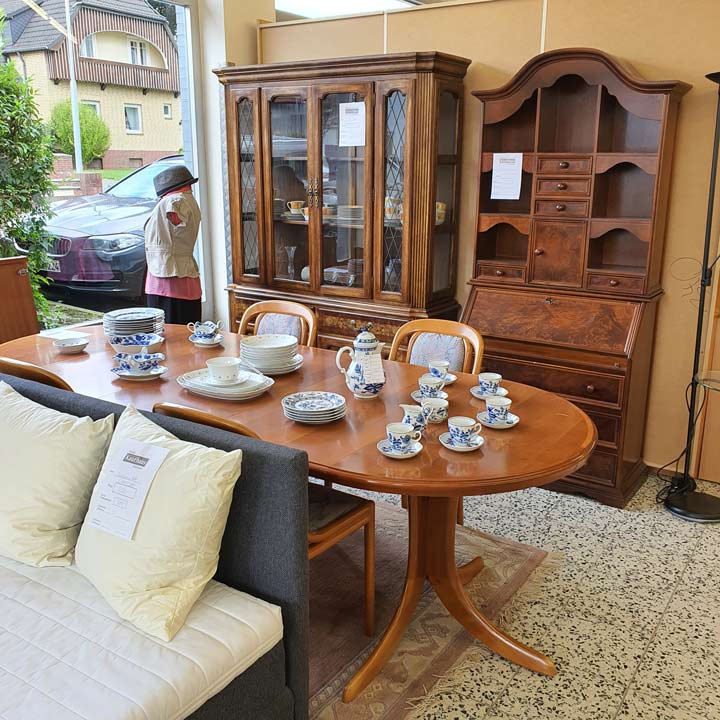 Sozialkaufhaus Reinfeld - Esstisch mit Geschirr, im Hintergrund Vitrine aus Echtholz